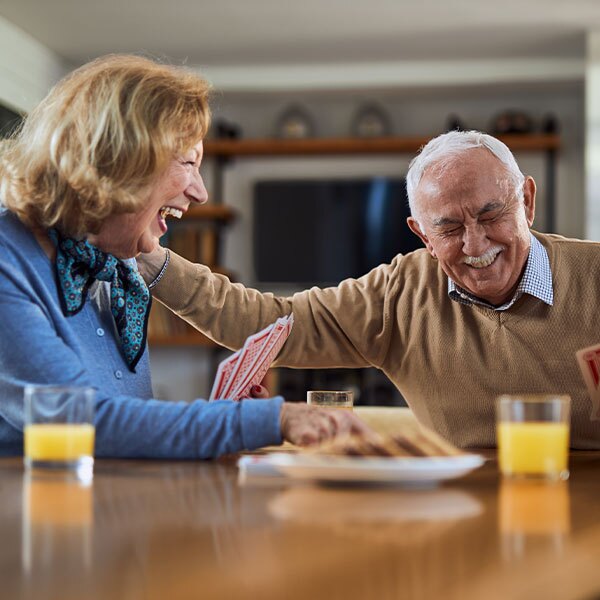 older couple joyfully laughing together at a table, enjoying each other's company.