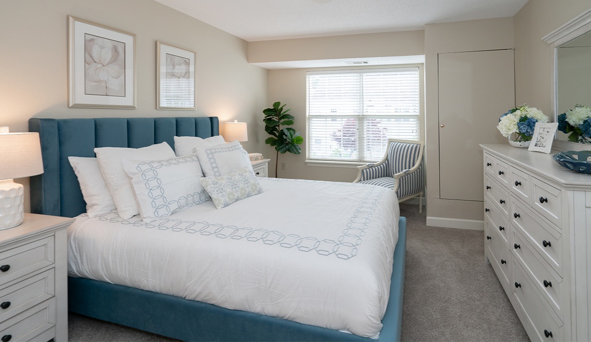 bedroom featuring a blue headboard and a neatly made white bed.