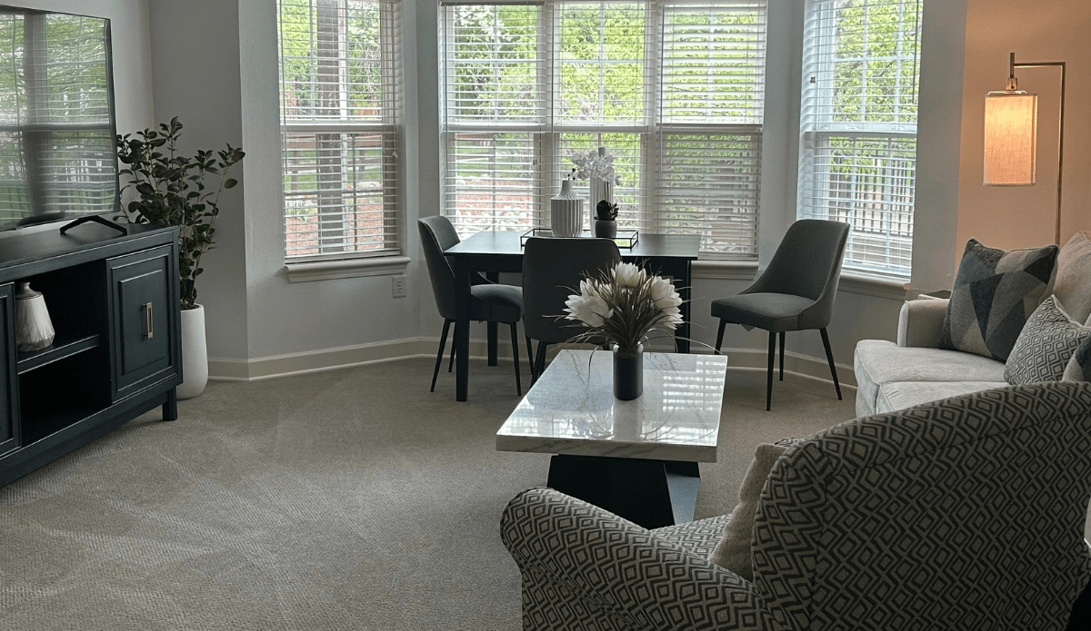Living room featuring a couch, a table with chairs, and a television on the wall.